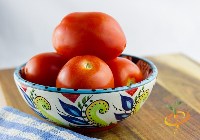 Bright red medium Rutgers tomatoes in decorative bowl on wooden surface