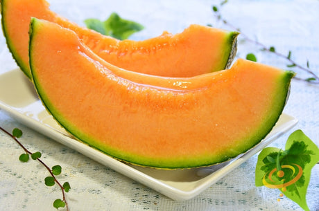 Hales Best Jumbo cantaloupe melon seeds by SeedsNow, showing vibrant orange ripe melon with green rind in a garden setting.